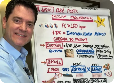 Dr. Eric Rulli ao lado de um flipchart explicando checklist de taquiarritmias