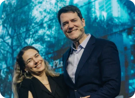 Dr. Eric Rulli sorrindo ao lado de uma colega no palco de um evento