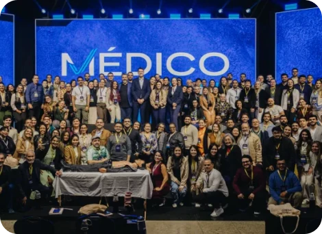 Dr. Eric Rulli em foto de grupo no palco com centenas de participantes de um evento